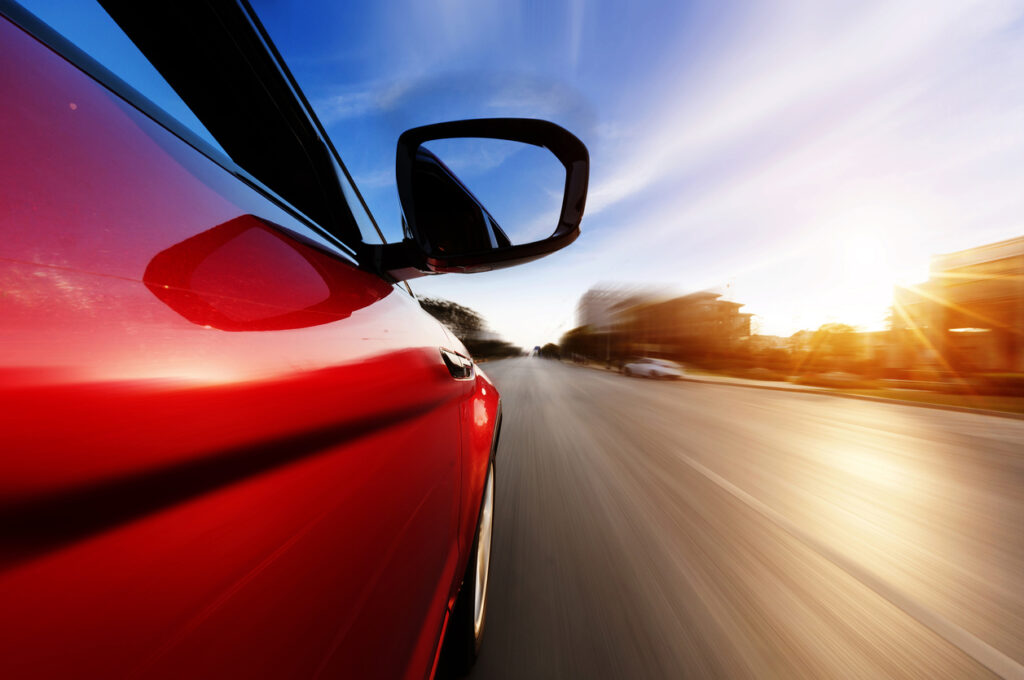 Side view of a car in motion with a blurred road, representing speed