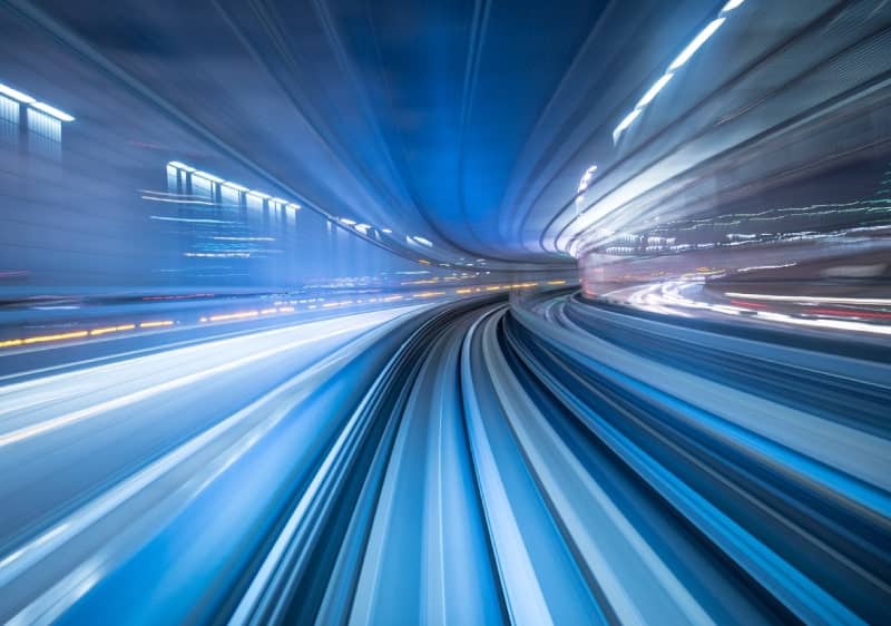 Long exposure of a train in motion through a tunnel with dynamic light streaks indicating speed